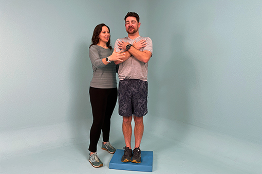 Angie Blaikie assists a patient balancing on a block. 