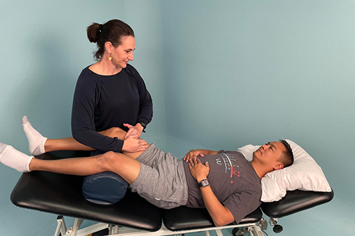 Brigit Lim massages a patient's leg as he lie on a treatment table. 