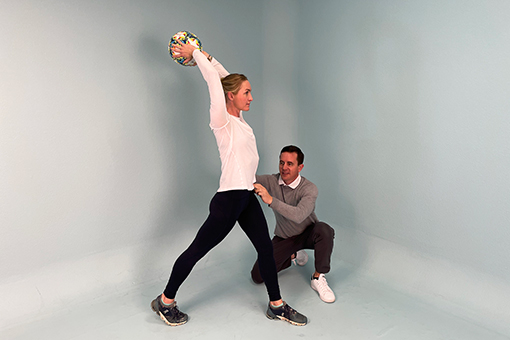 Eric coaches a patient through throwing a soccer ball. 