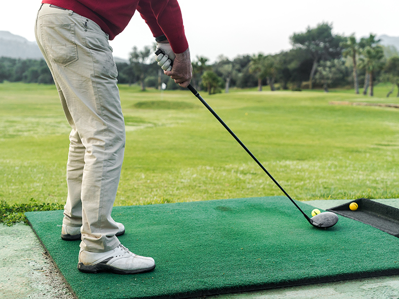 A golfer positions himself to swing a golf club. 