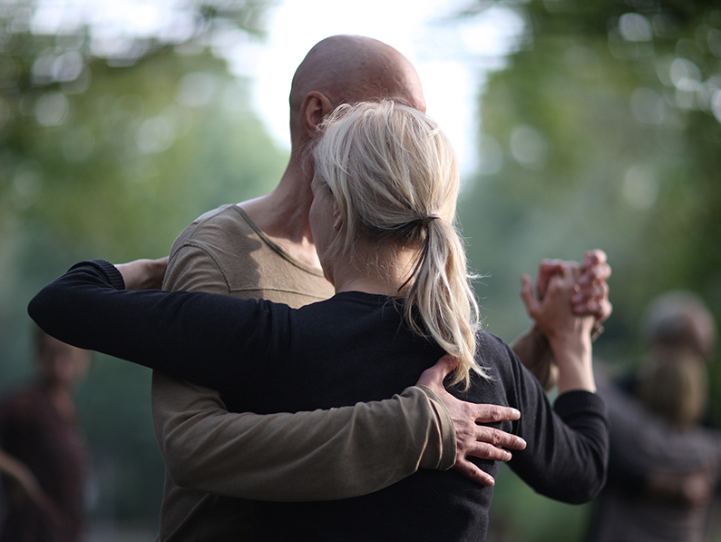 A man and woman ballroom dance outdoors. 