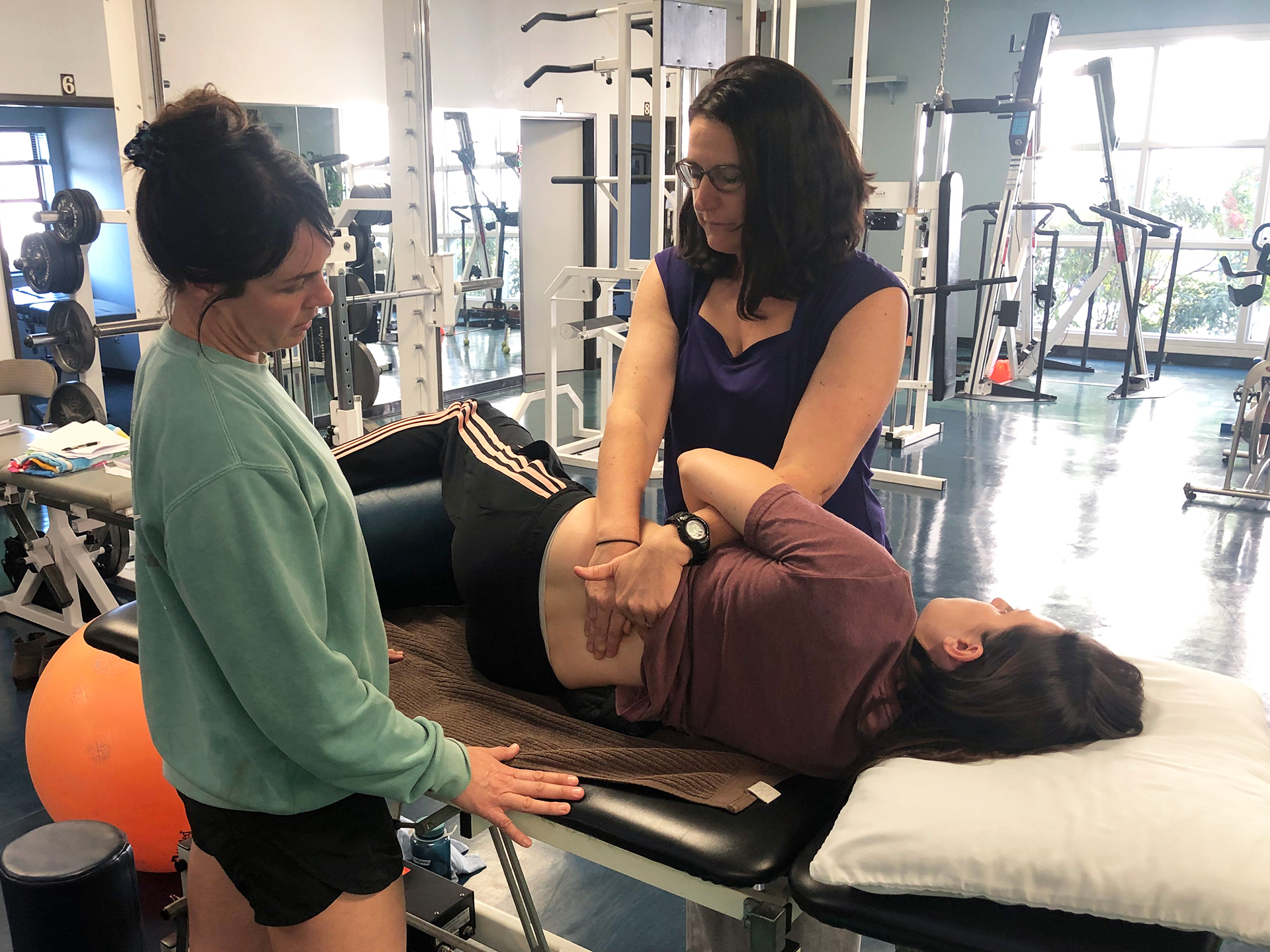 Brigit Lim instructs a student in spine treatment using a model lying on a table.
