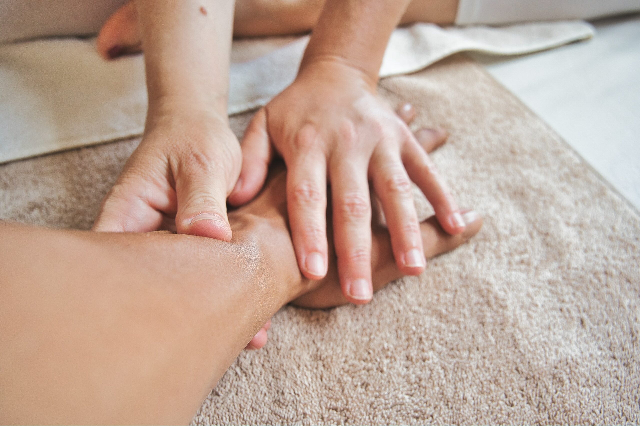 A massage therapist's hands massages a client's hand.